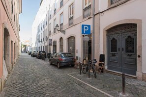 A cobblestone street lined with buildings, a parked car, and a bicycle. - Attic Bairro Alto (Lisbon)
