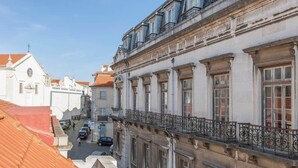 Een gebouw met klassieke architectuur, voorzien van een balkon met smeedijzeren hekwerk en een straatbeeld eronder.