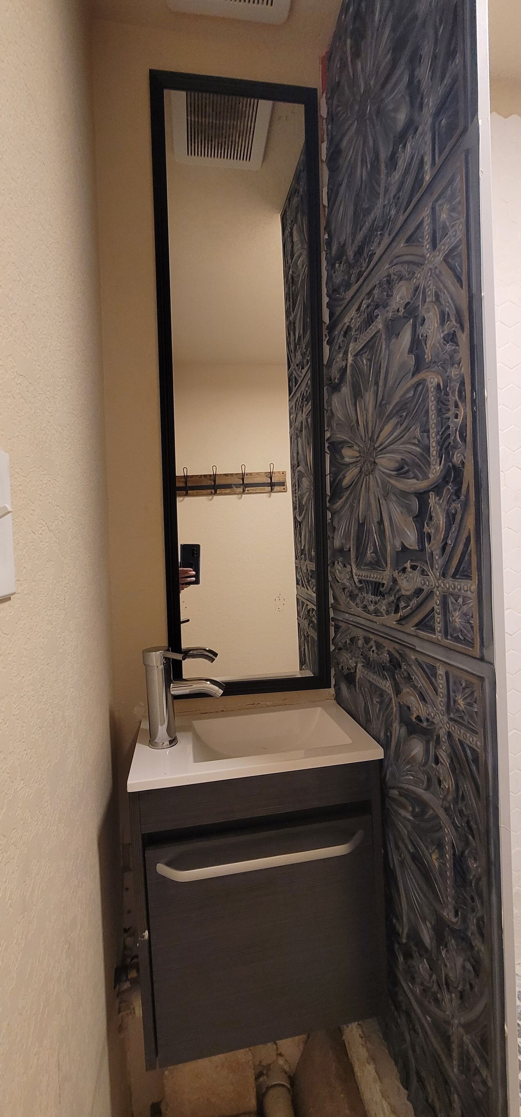 A bathroom with a sink, mirror, and decorative wall paneling.
