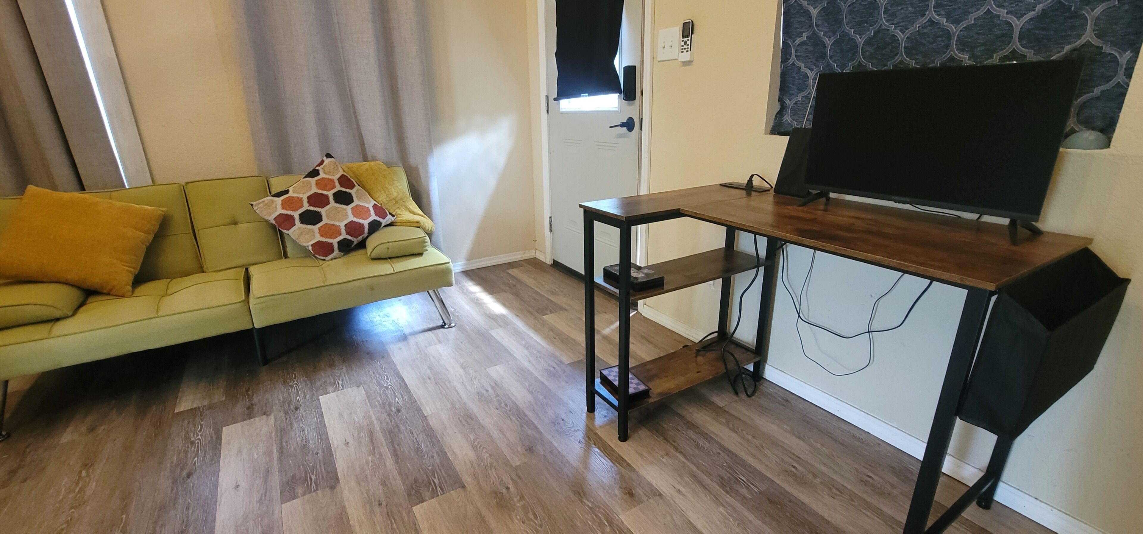 Un salon comprenant un canapé, une table basse, un téléviseur posé sur un meuble et une porte avec un interrupteur.