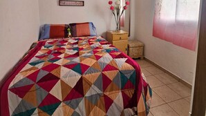 Una camera da letto con un letto, un comodino, uno specchio e una parete con una tenda a fiori.