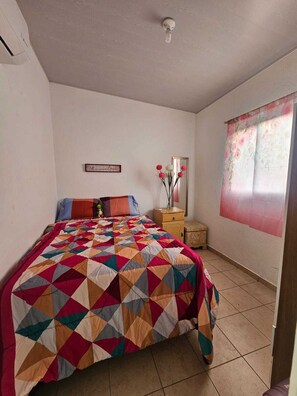 Ein Schlafzimmer mit einem Bett, einem Nachttisch, einem Spiegel und einer Wand mit einem blumigen Vorhang.