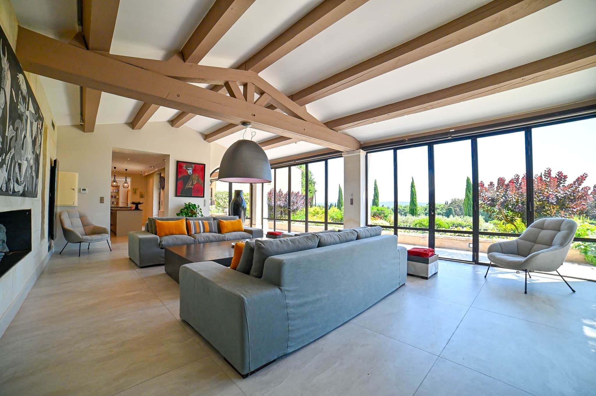 A spacious living area with a large sectional sofa, a dining table, and a modern chandelier.