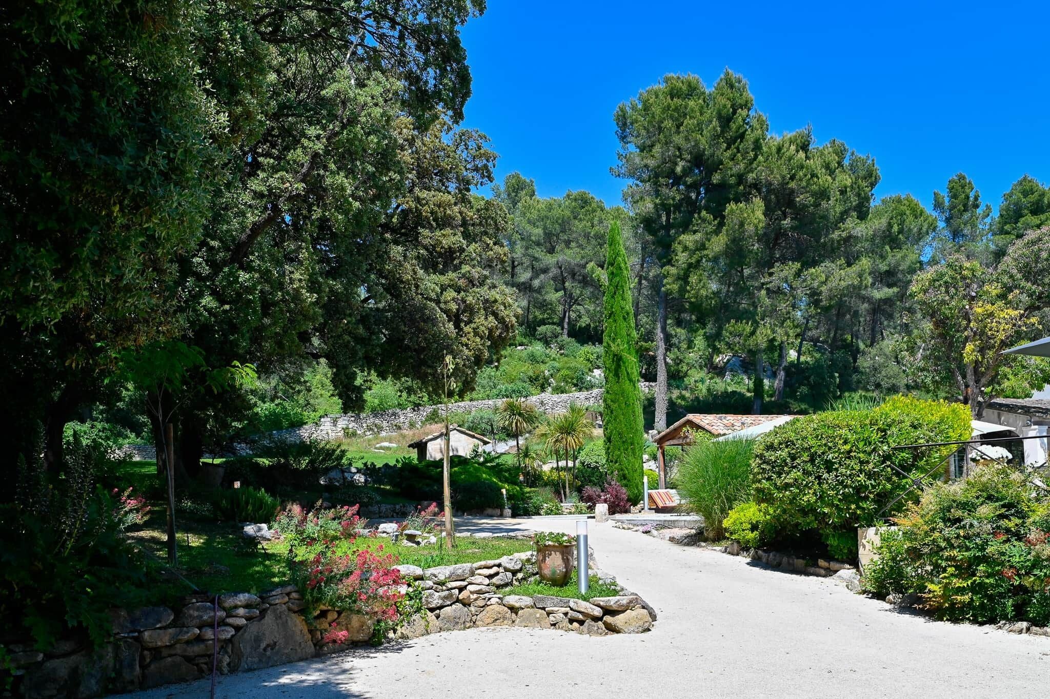 Un sendero serpentea por un jardín con muros de piedra y diversas plantas.