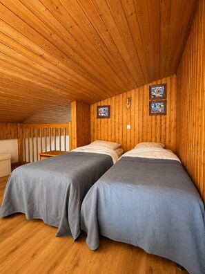 A room with two beds, wooden walls, and a sloped ceiling. - Panoramic view • Downtown and walking trails • Serves 6 (Châtel)