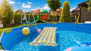 En pool som står ovan jord, med en vattenrutschkana, en uppblåsbar badleksak och en leksak med delfintema.