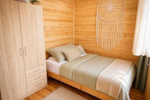 Een houten kamer met een bed, een kledingkast en een dreamcatcher aan de wand.