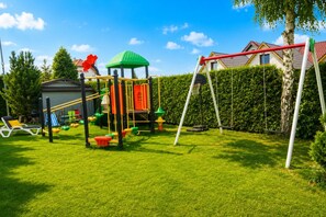 Ein Spielplatz mit Rutsche, Klettergerüsten und Schaukeln.