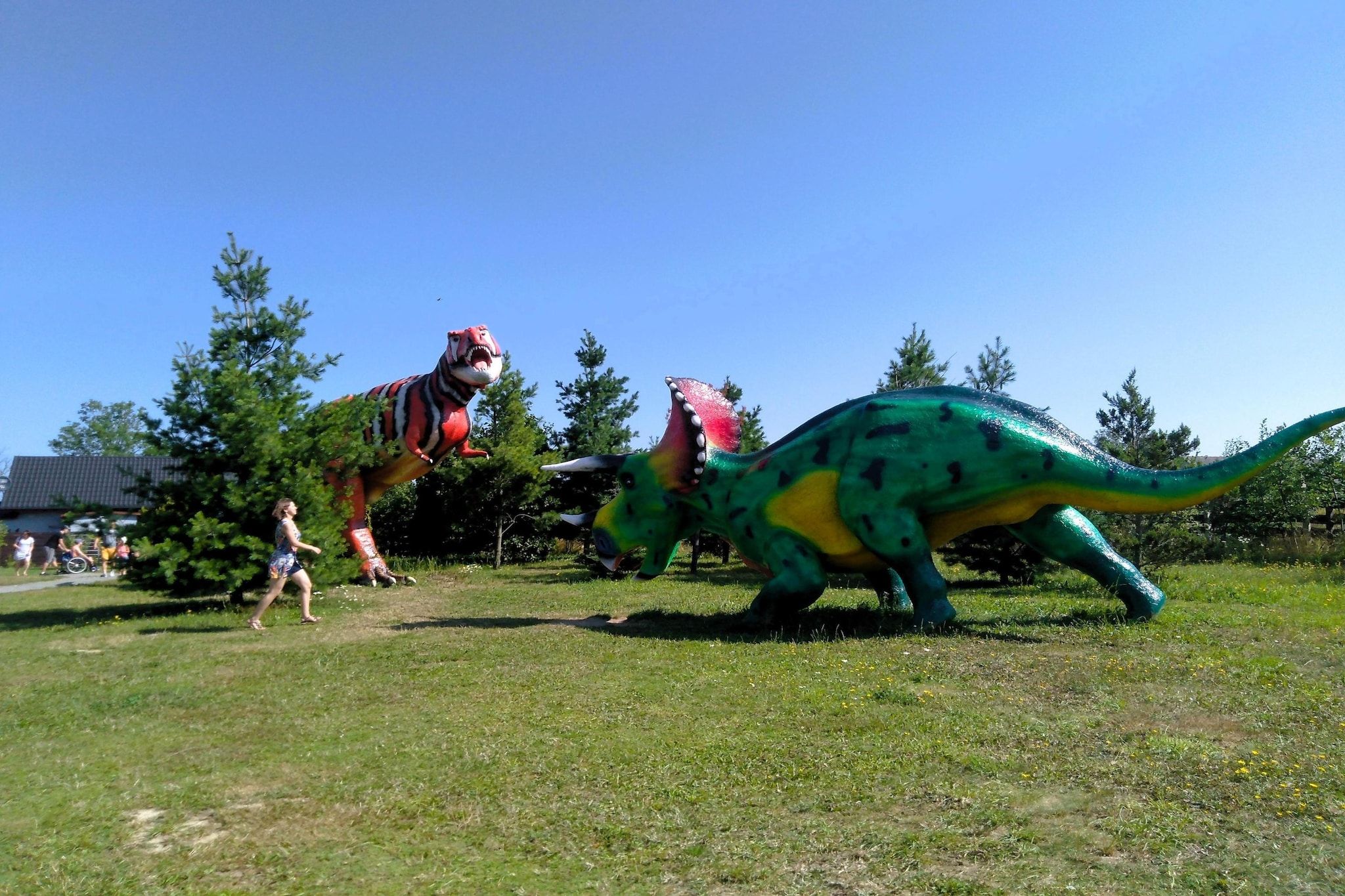 A grassy outdoor area with two large dinosaur sculptures.