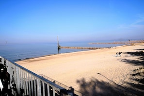 Ein Strand mit einer Holzbrücke, einem Steg und ruhigem Meer.