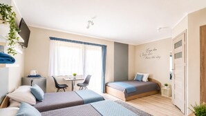 Et hotelværelse med to senge, et skrivebord, en stol og et lille bord.