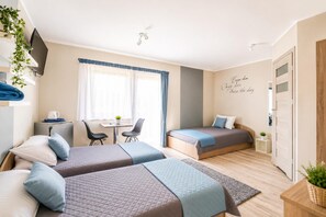 Ein Hotelzimmer mit zwei Betten, einem Schreibtisch, einem Stuhl und einem kleinen Tisch.