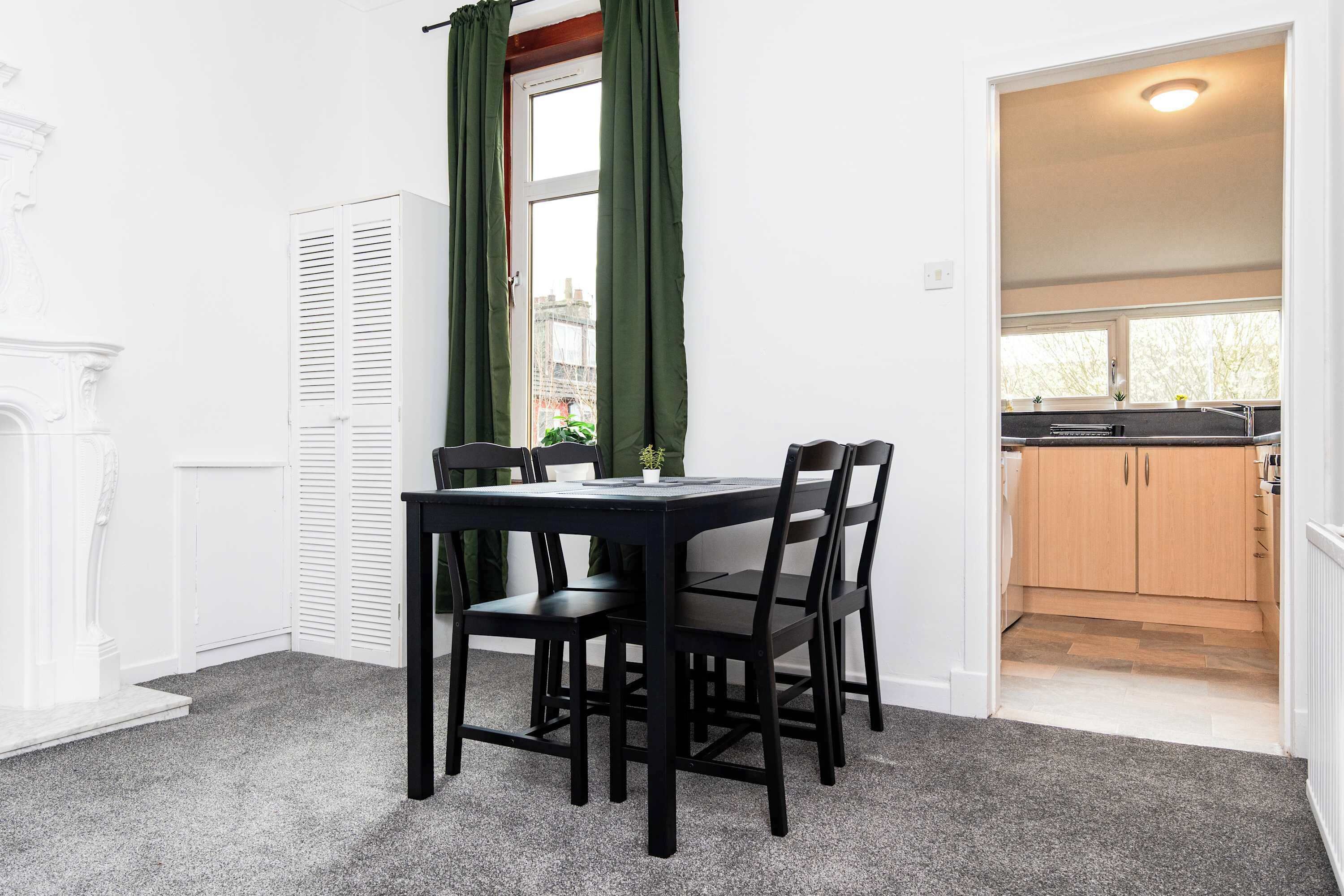 A dining area with a table and chairs, a window with curtains, and a view of the outside.