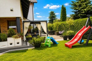 A residential outdoor area with a patio, seating, a slide, and a pergola. - Studio for 3 people, close to the sea (Dziwnówek)