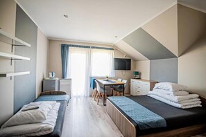 A modern, well-lit bedroom with two beds, a desk, and a TV. - Studio for 3 people, close to the sea (Dziwnówek)