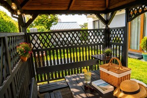 A wooden deck with a bench, a table with a drink, a basket, and a book. - Studio for 3 people, close to the sea (Dziwnówek)