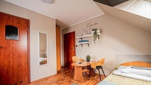 A bedroom with a bed, a desk, two chairs, a mirror, and a door. - Studio for 2 people, close to the sea (Dziwnówek)