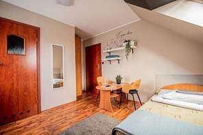 A bedroom with a bed, a desk, two chairs, a mirror, and a door. - Studio for 2 people, close to the sea (Dziwnówek)