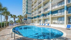 A hotel pool area with a clear blue pool, lounge chairs, and a multi-story building with balconies. - Carolinian Beach Resort 1731 (Myrtle Beach)