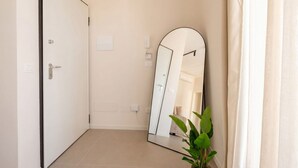 A room with a closed door, a large mirror, a potted plant, and a light switch on the wall. - ALL Gargasole | Luxury Sky-High Retreat with 2 Private Terraces (Bari)