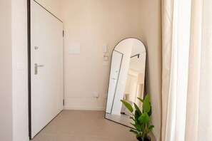 A room with a closed door, a large mirror, a potted plant, and a light switch on the wall. - ALL Gargasole | Luxury Sky-High Retreat with 2 Private Terraces (Bari)