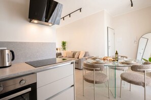 A modern kitchen with a built-in oven, a coffee maker, and a dining area with a glass table and cushioned chairs. - ALL Gargasole | Luxury Sky-High Retreat with 2 Private Terraces (Bari)