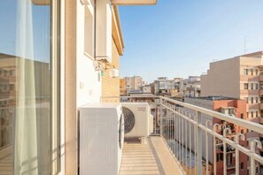A balcony with a view of a cityscape, an air conditioning unit, and a window with a curtain. - ALL Gargasole | Luxury Sky-High Retreat with 2 Private Terraces (Bari)