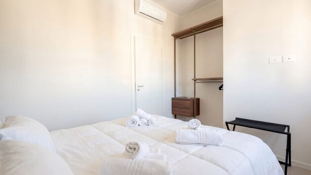 A hotel room with a bed, a bedside table, a mirror, and an air conditioning unit. - ALL Gargasole | Luxury Sky-High Retreat with 2 Private Terraces (Bari)