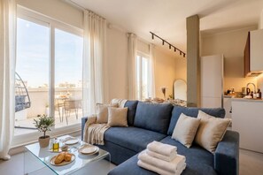 A modern living room with a sofa, a glass coffee table, and a view of the city. - ALL Gargasole | Luxury Sky-High Retreat with 2 Private Terraces (Bari)