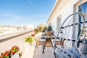 A rooftop terrace with a dining table, chairs, a hanging chair, and potted plants. - ALL Gargasole | Luxury Sky-High Retreat with 2 Private Terraces (Bari)