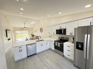 Een moderne keuken met witte kastjes, roestvrijstalen apparatuur en een centraal keukenblok met een spoelbak.