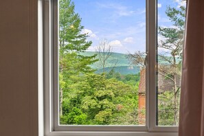 A window with a view of a forested landscape and a brick chimney. - Cozy Bryce Resort Condo - Fireplace & Views (Basye)