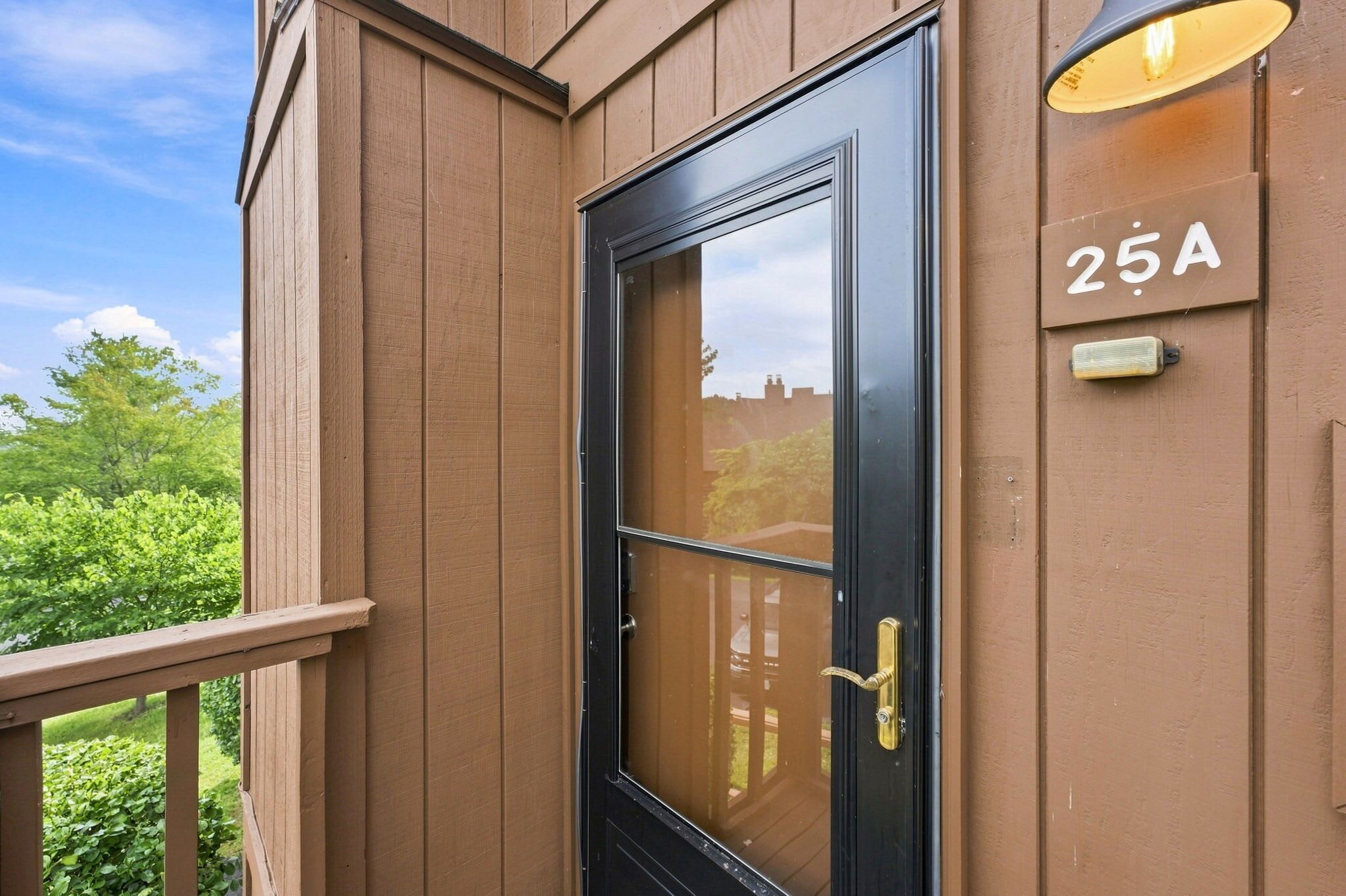 A brown building with a black door, a balcony, and a mailbox with the number 25A.