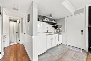 Una cocina moderna con armarios blancos, estufa de acero inoxidable y horno empotrado.
