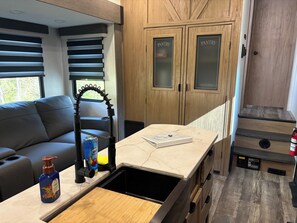 A compact kitchenette with a countertop, a sink, and wooden cabinets labeled 'PANTRY.' - Mountain Hideaway - 2 br 1.5 ba RV (Watauga, TN)