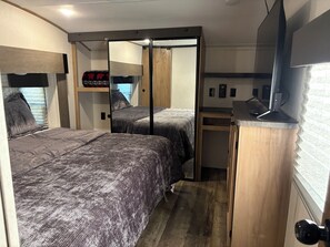 Una habitación compacta con dos camas, un escritorio y un televisor.