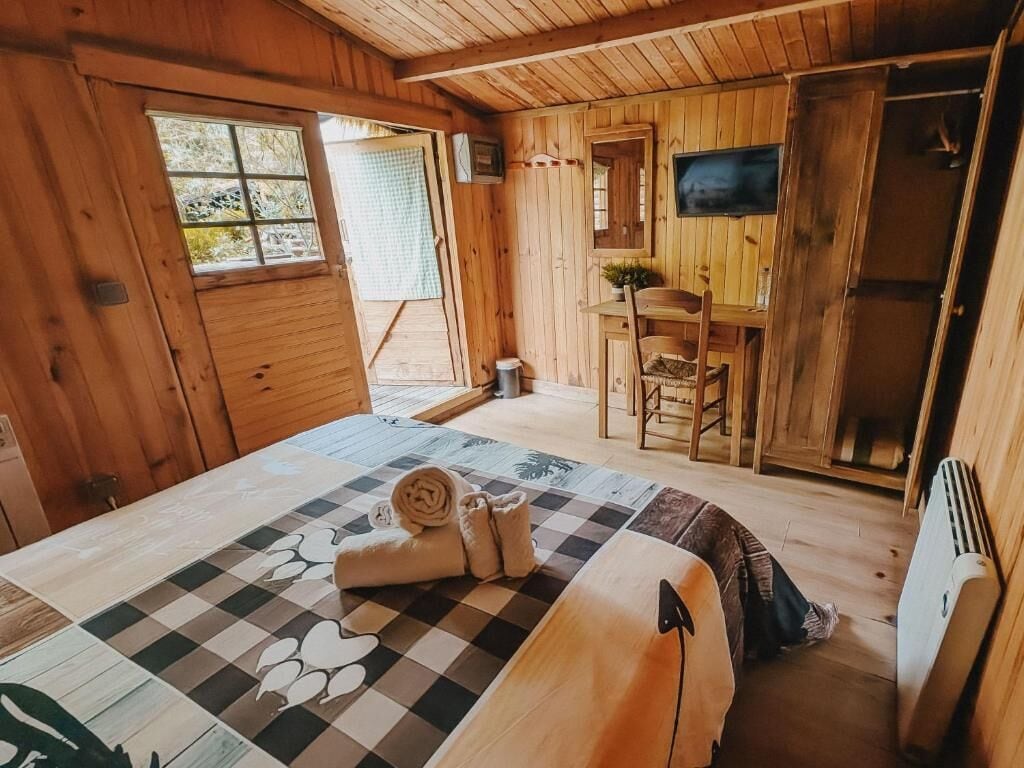 A wooden room with a bed, a desk, and a chair.