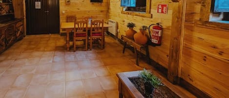 A wooden interior with a dining area, a fireplace, and a fire extinguisher.