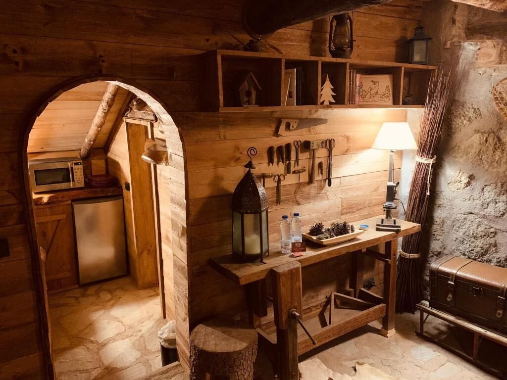 A rustic kitchen with wooden walls, a built-in microwave, and a small refrigerator.
