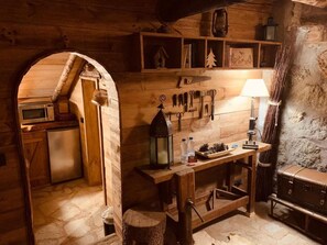 Una cocina rústica con paredes de madera, un microondas empotrado y un refrigerador pequeño.