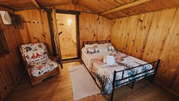 A wooden room with a bed, a chair, and a door.