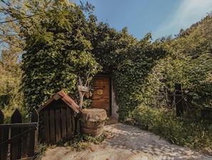 Un edificio de madera rústico con un letrero, un barril y una valla de madera en un jardín.