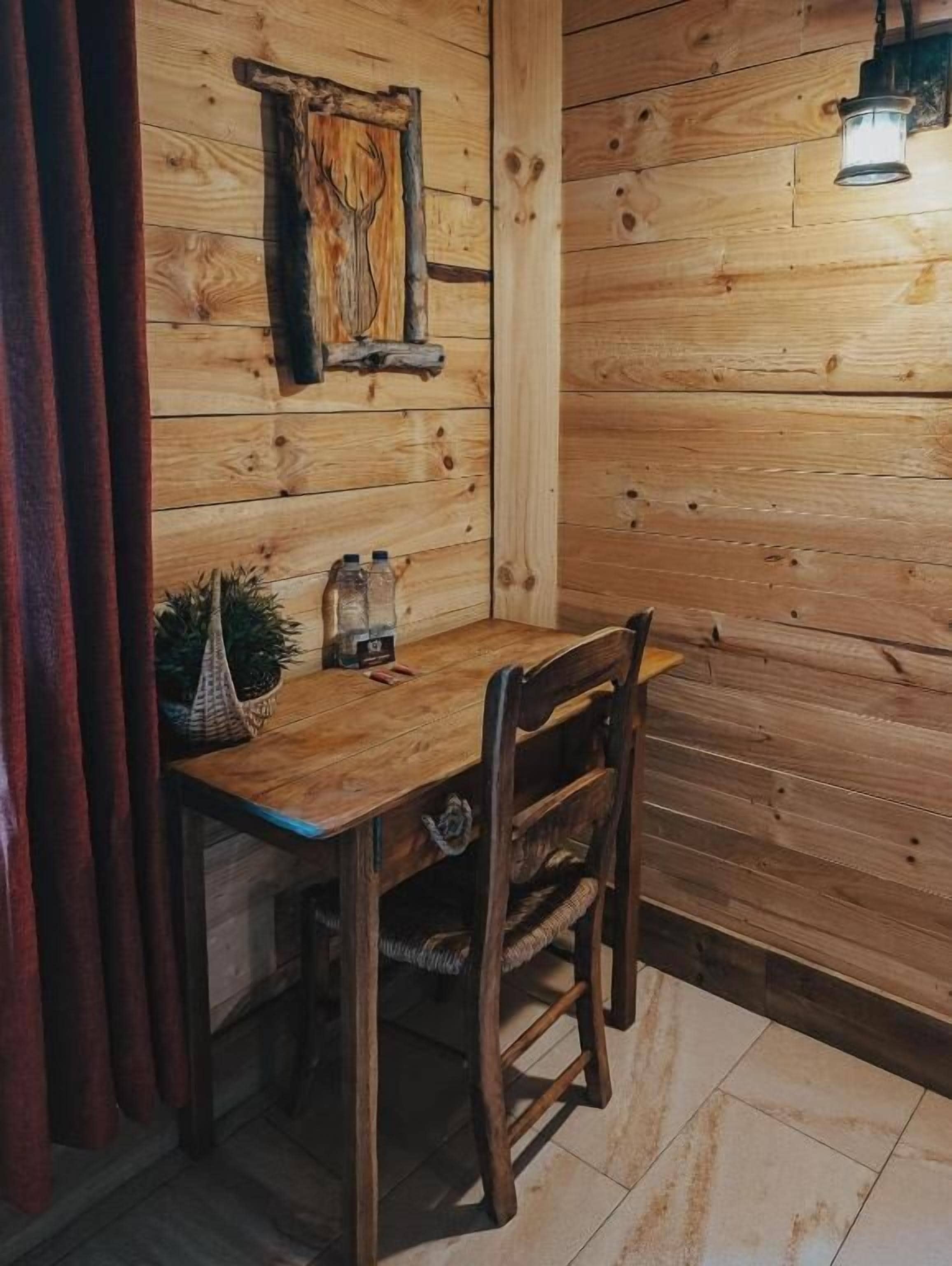 Ein Holzinterieur mit einem Tisch, Stühlen, einer Pendelleuchte und einem Wandbild.