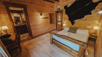 Habitación de cabaña de madera con una cama, un banco de madera y un tapiz de cuero de vaca en la pared.