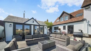 A patio area with outdoor furniture, a glass-enclosed structure, and a barbecue grill.
