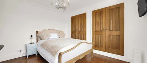 Ein Schlafzimmer mit einem hölzernen Bett, einem Nachttisch, einer Kristallleuchtre und Holzschränken.