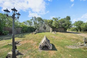 Ein steinernes Gebäude, das einer kleinen Kirche oder Kapelle ähnelt, mit einem Rasen, einem Holzzaun und einer Straßenlaterne.