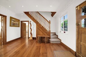 Eine Holztreppe mit Geländer, die zu einer Empore mit einer Bank und einer Tür führt.