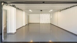 Un garatge net i buit amb un sòl polit, parets blanques i un conjunt de portes dobles al centre.
