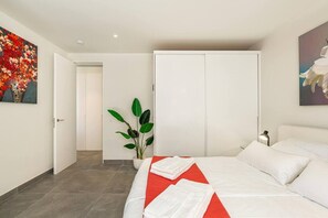 Una habitación de hotel con una cama, una planta en maceta y obras de arte en las paredes.